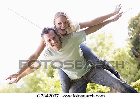 Man giving woman piggyback ride outdoors smiling View Large Photo Image Stock Photo - Man giving woman piggyback ride outdoors smiling. Fotosearch