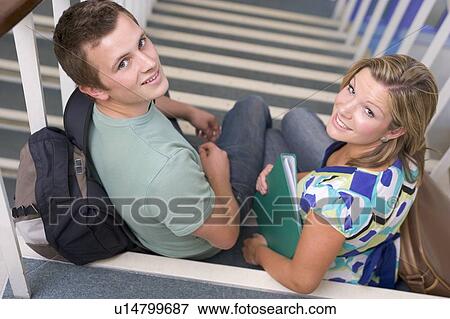 Stock Photo - Two students sitting on staircase with notebooks (selective focus). Fotosearch