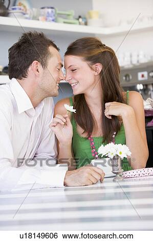 Young couple sitting at a table looking into each other's eyes View Large Photo Image Stock Photograph - Young couple sitting at a table looking into each other's eyes. Fotosearch
