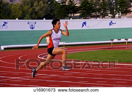 Stock Image - Female athlete running on race track. Fotosearch