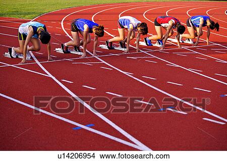 Picture - Five female athletes in starting positions on running track. Fotosearch