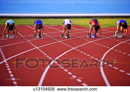 Stock Photo - Five female athletes in starting positions on running track. Fotosearch