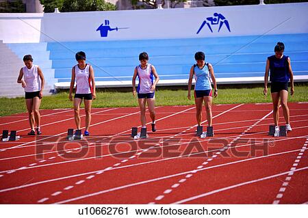 Stock Image - Five female athletes standing on running track. Fotosearch