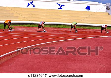 Stock Photo - Four male athletes getting ready to run. Fotosearch