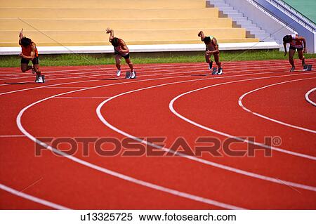 Stock Photography - Four male athletes running from the track starting block. Fotosearch