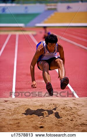 Stock Image - Male athlete long jumping, mid-air. Fotosearch