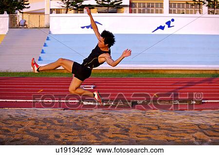 Stock Image - Male athlete long jumping, mid-air. Fotosearch