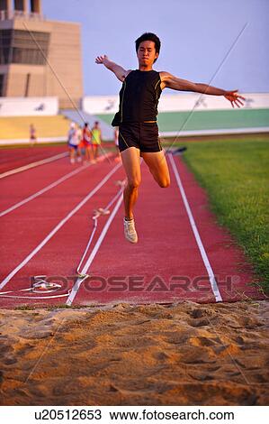 Stock Image - Male athlete long jumping, mid-air. Fotosearch