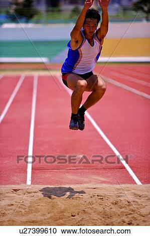 Stock Image - Male athlete long jumping, mid-air. Fotosearch