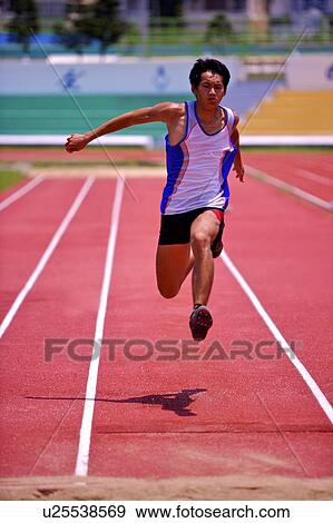 Stock Photo - Male athlete long jumping, mid-air. Fotosearch