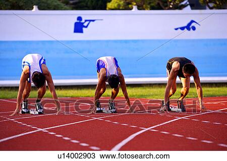Three male athletes in starting positions on running track View Large Photo Image Stock Image - Three male athletes in starting positions on running track. Fotosearch
