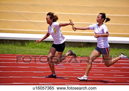 Stock Photography - Two female athletes passing relay baton. Fotosearch