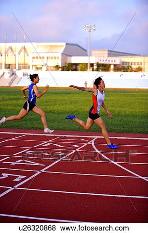 Stock Photo - Two female athletes running to the finish line. Fotosearch