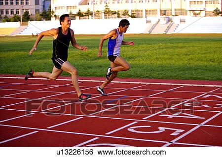 Stock Photograph - Two male athletes running to the finish line. Fotosearch