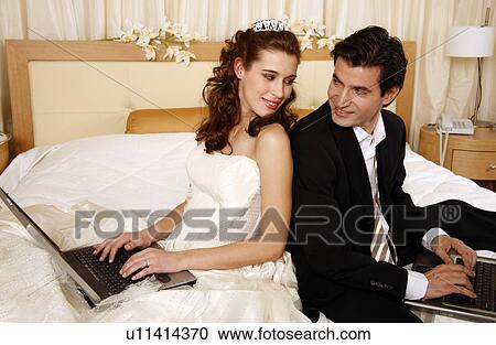Stock Image - Bride and groom on laptops. Fotosearch