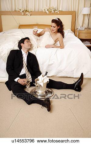 Stock Photograph - Bride and groom toasting in hotel room. Fotosearch