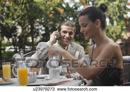 Stock Image - Business couple in garden cafe. Fotosearch