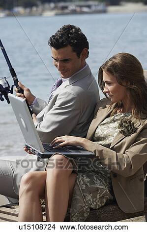 Business couple on beach with fishing rod and laptop View Large Photo Image Picture - Business couple on beach with fishing rod and laptop. Fotosearch