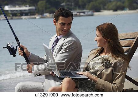 Business couple on beach with fishing rod and laptop View Large Photo Image Stock Image - Business couple on beach with fishing rod and laptop. Fotosearch