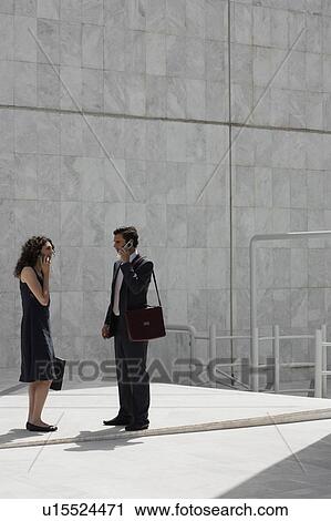Stock Image - Businessman and businesswoman on cell phones meeting. Fotosearch
