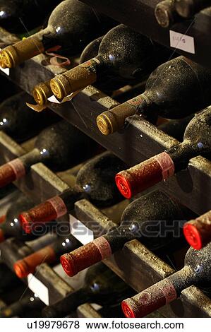 Stock Photo - Dusty wine bottles on a rack. Fotosearch