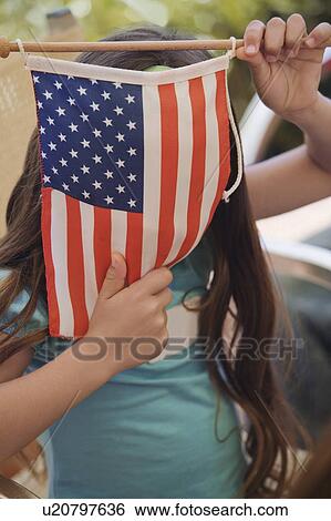 Stock Photograph - Girl hiding behind American flag. Fotosearch