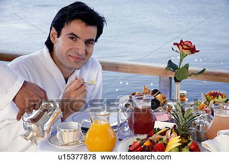 Stock Photo - Man having breakfast on hotel terrace. Fotosearch