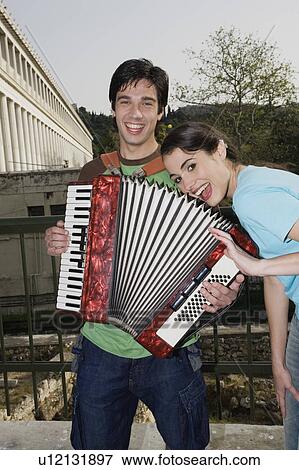 Stock Photo - Man playing accordion with woman smiling. Fotosearch