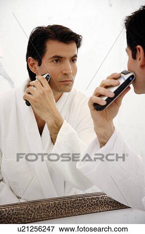 Stock Photo - Man shaving in the bathroom mirror. Fotosearch