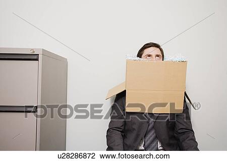 Stock Image - Office worker with head in a box. Fotosearch