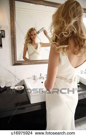 Picture - Woman drying her hair in bathroom. Fotosearch