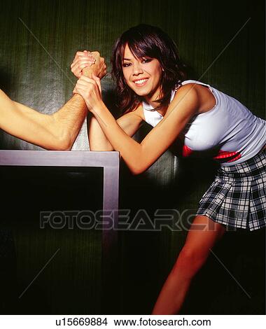 Picture - Young woman arm wrestling with man. Fotosearch