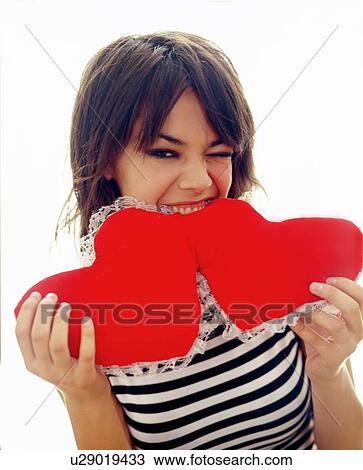 Young woman biting on hearts pillow View Large Photo Image Stock Image - Young woman biting on hearts pillow. Fotosearch