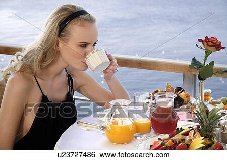 Stock Photograph - Young woman having breakfast on hotel terrace. Fotosearch