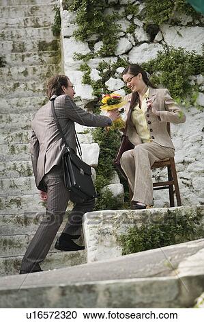 Stock Image - Businessman giving businesswoman flowers. Fotosearch