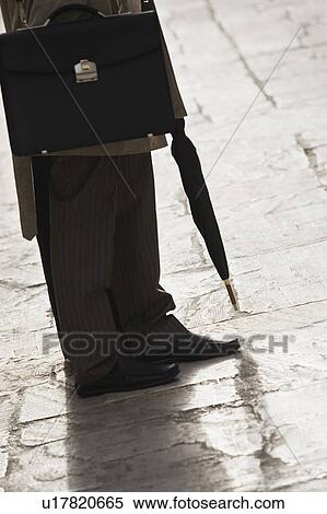 Stock Photography - Businessman with umbrella, waist down. Fotosearch