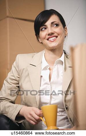 Picture - Businesswoman with a cup of coffee among boxes. Fotosearch
