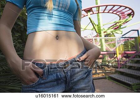 Stock Image - Closeup of female teenager's pierced belly button at amusement park. Fotosearch