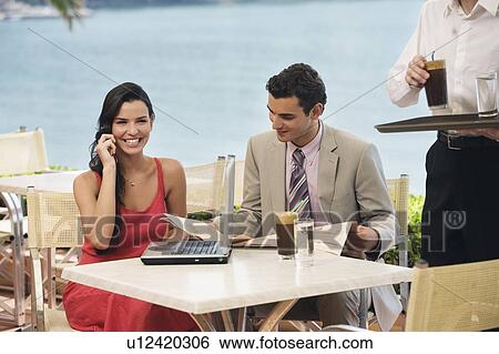 Stock Photograph - Couple at seaside cafe table with laptop. Fotosearch