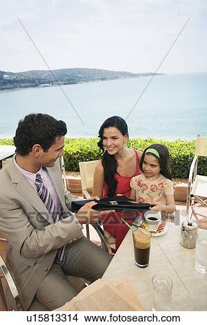 Couple with daughter at seaside cafe table View Large Photo Image Picture - Couple with daughter at seaside cafe table. Fotosearch