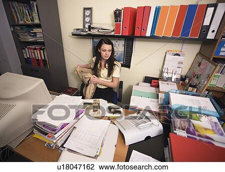 Female office worker at cluttered desk View Large Photo Image Stock Image - Female office worker at cluttered desk. Fotosearch