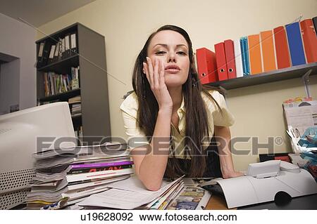 Female office worker at cluttered desk View Large Photo Image Stock Image - Female office worker at cluttered desk. Fotosearch