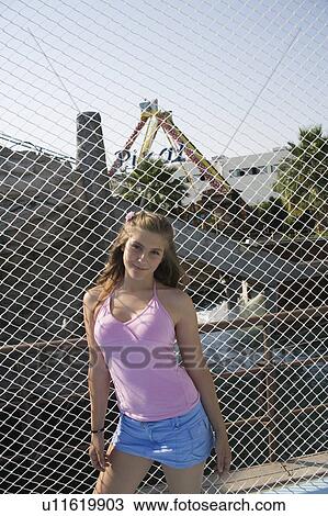 Stock Image - Female teenager posing at fence. Fotosearch