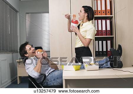 Male and female office workers eating take out food View Large Photo Image Stock Photo - Male and female office workers eating take out food. Fotosearch