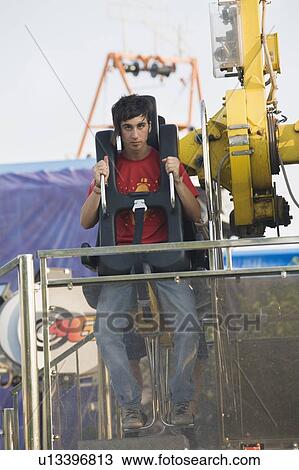 Stock Image - Male teenager on amusement park ride. Fotosearch