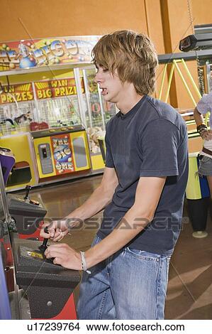 Male teenager playing game in arcade View Large Photo Image Picture - Male teenager playing game in arcade. Fotosearch