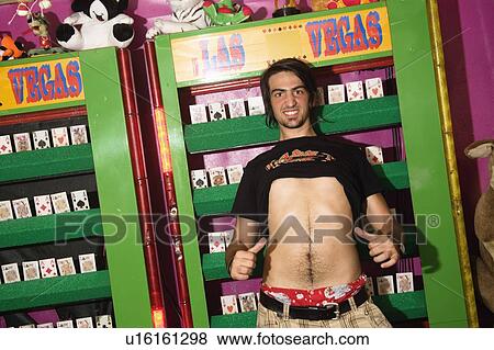Stock Photo - Male teenager posing with lifted shirt at game in amusement park. Fotosearch