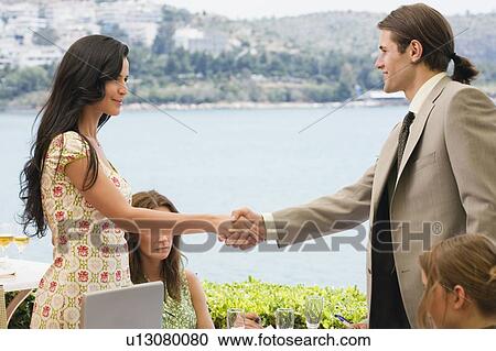 Stock Image - Man and woman shaking hands at seaside meeting. Fotosearch