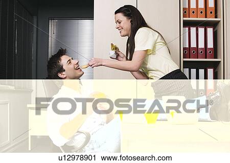 Office worker feeding her colleague at desk View Large Photo Image Stock Image - Office worker feeding her colleague at desk. Fotosearch