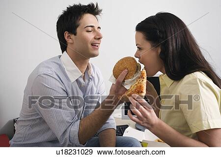 Office worker feeding his colleague at desk View Large Photo Image Stock Photo - Office worker feeding his colleague at desk. Fotosearch